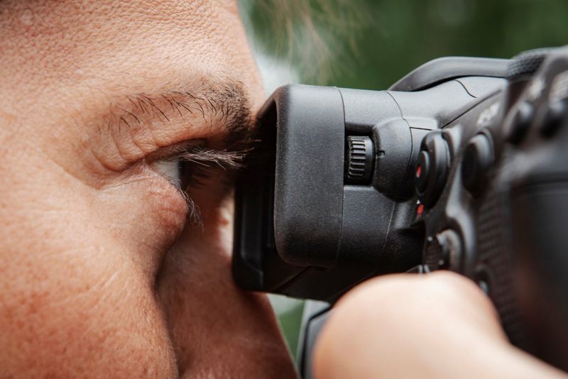 A close-up of an eye looking into the viewfinder of a Canon EOS R3 camera.
