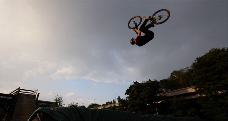 A mountain biker mid-stunt, silhouetted against the sky.
