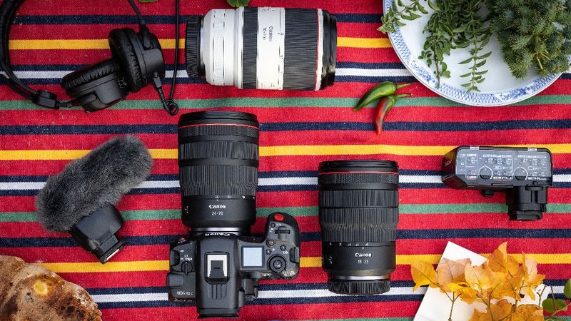 A top-down shot of Canon cameras, lenses and accessories arranged on a striped surface.