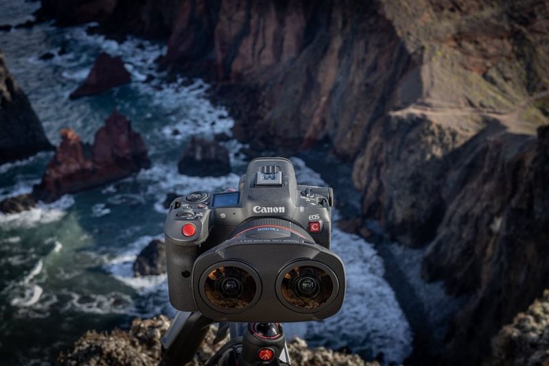 A Canon EOS R5 C hybrid camera, with an RF 5.2mm F2.8L Dual Fisheye lens attached, mounted on a tripod overlooking the sea. 