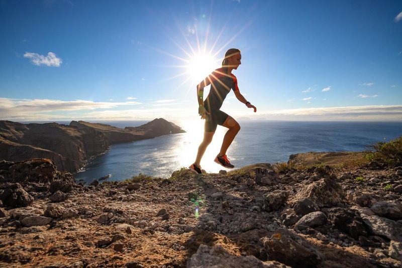 A figure in a wetsuit is captured ascending a rocky cliff in an image taken on a Canon EOS R5 C with a Canon RF 15-35mm F2.8L IS USM lens.