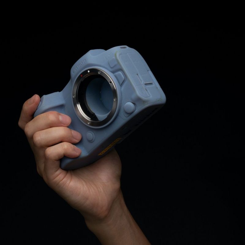A hand holds a mockup of a Canon EOS R5 camera.