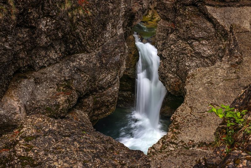 A waterfall tumbles into a pool in the rocks, shot using a long exposure to blur the falling water.