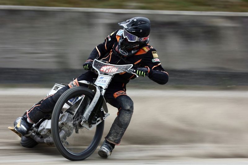 A motorbike and rider skid along a track, leaning heavily to the side.