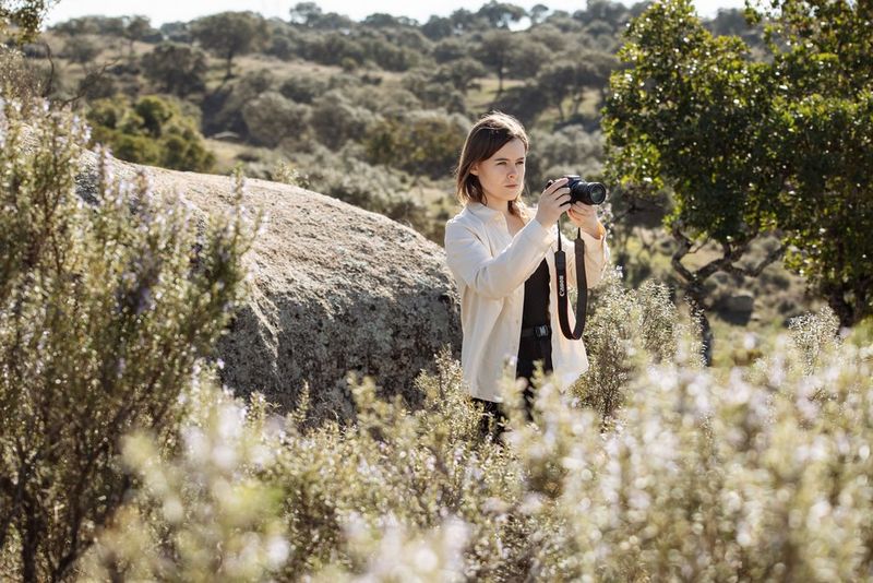 Dani Connor stands taking photographs in a field with a Canon camera and RF lens.