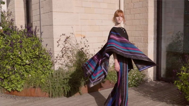 A woman in a colourful poncho swirling around, filmed on a Canon EOS R8.