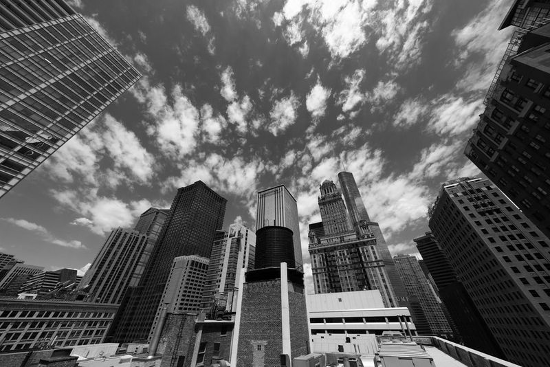A black and white image of the sky filled with skyscrapers and tall city buildings.