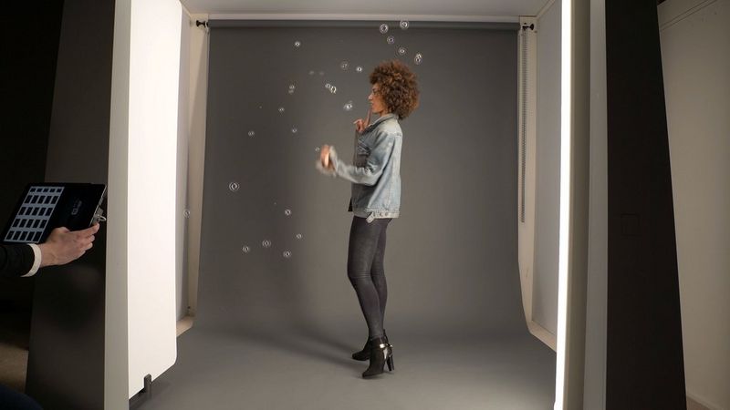 A curly-haired female model in a StyleShoots photography machine, surrounded by bubbles.