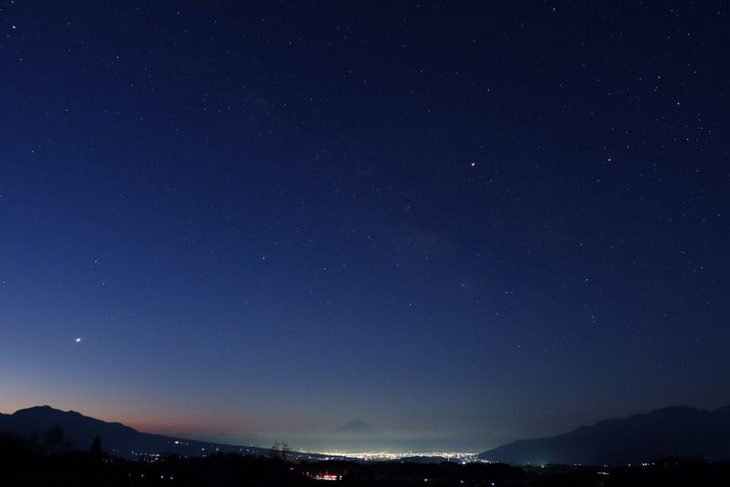 A long exposure, taken on a Canon PowerShot G7 X Mark III, of distant city lights under a starry sky.