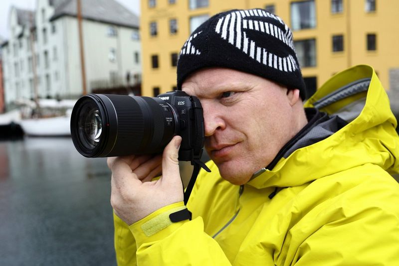 A man in a yellow waterproof coat taking a photo with a Canon EOS RP and Canon RF 24-240mm F4-6.3 IS USM lens.