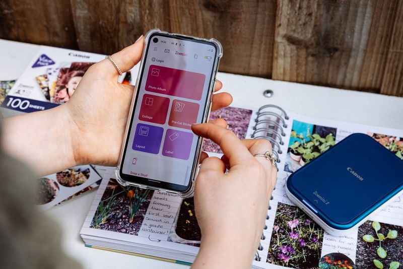 Hands holding a smartphone displaying the design options in the Canon Mini Print app.