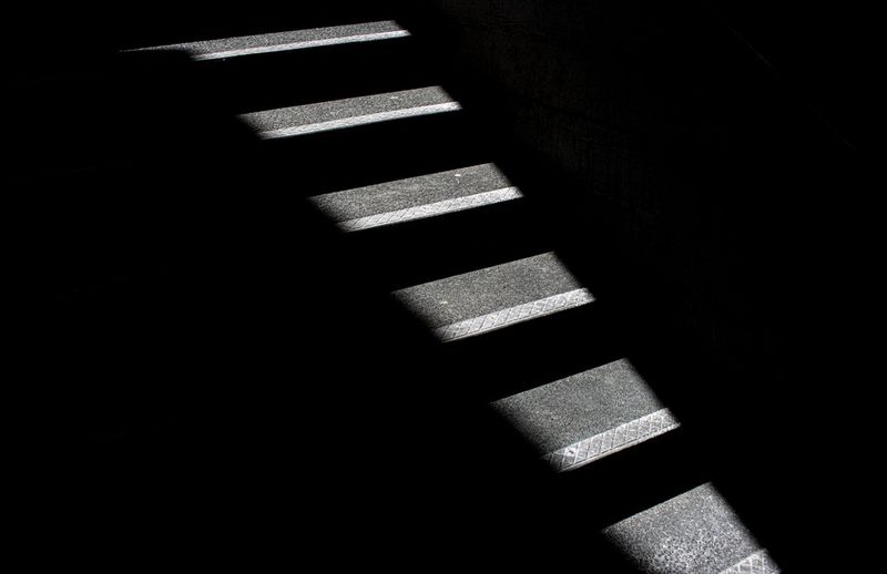 A stairwell in deep shadow, with only small portions of each step visible.