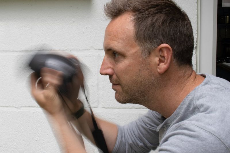 A man tilting his Canon camera up and down very quickly. 
