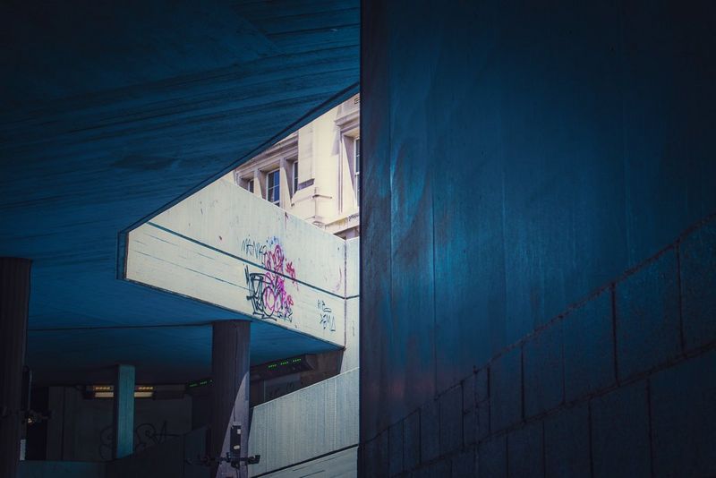 A shot taken in an underpass showing the light peeking through onto a graffitied wall. 