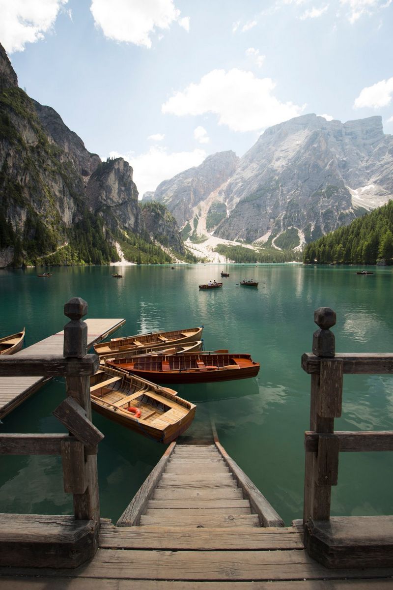 Lago di Braies in South Tyrol, Italy, looking towards the Dolomites in the background. Wooden steps and numerous small boats can be seen in the foreground.