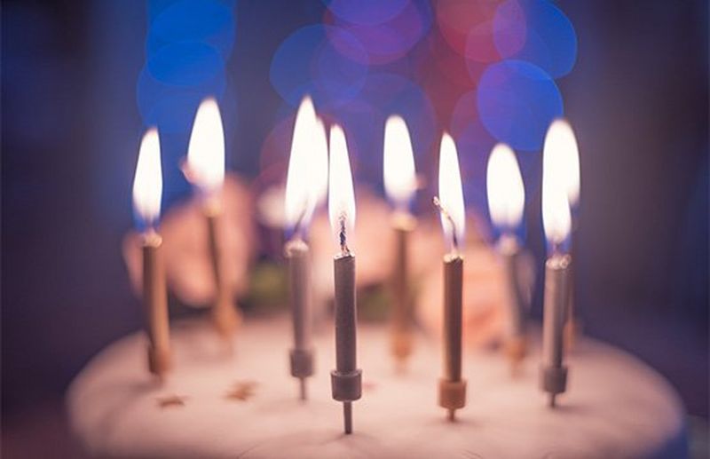 A close-up of some candles on a cake, with blurred lights in the background.