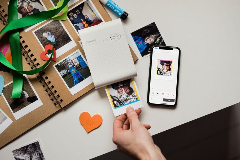 A Canon SELPHY Square QX10 printer on top of a scrapbook.