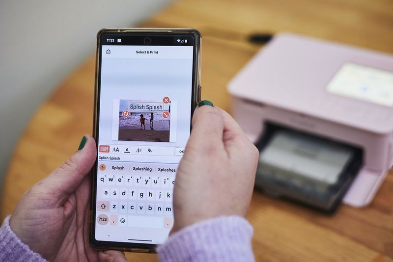 A close-up of hands holding a smartphone, showing the editing of a photograph in the Canon SELPHY Photo Layout app.