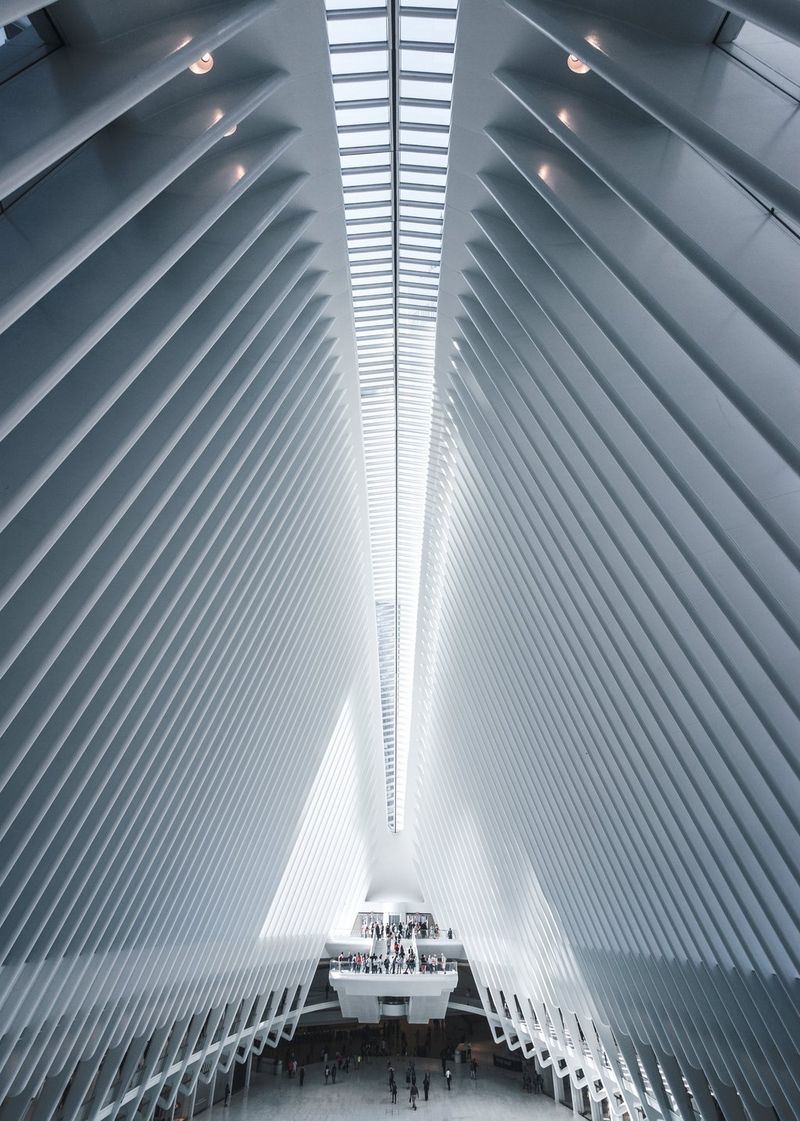 The inside of a large, white building, looking up at the roof and the rows of struts holding it up. 