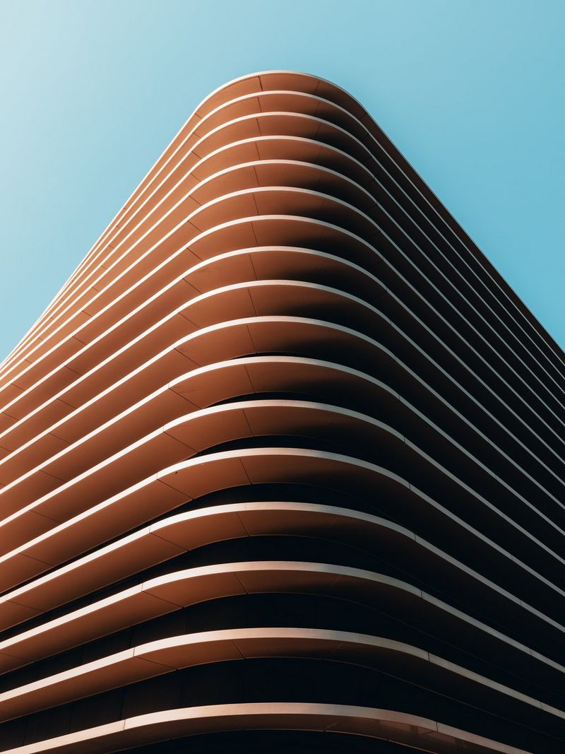 The corner of a building, with rows of curved sheeting jutting out from each floor.