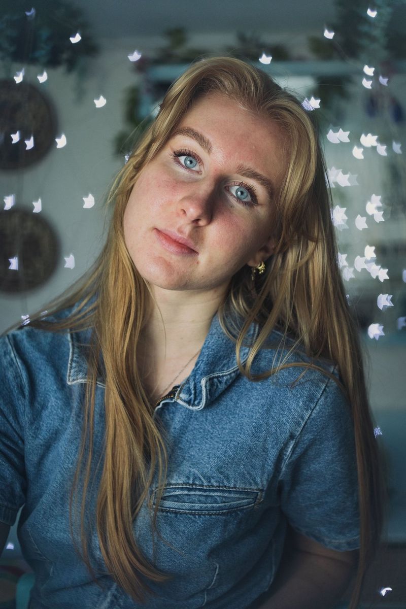 A self-portrait of a woman with her head tilted to one side and star-shaped bokeh clustered behind her.
