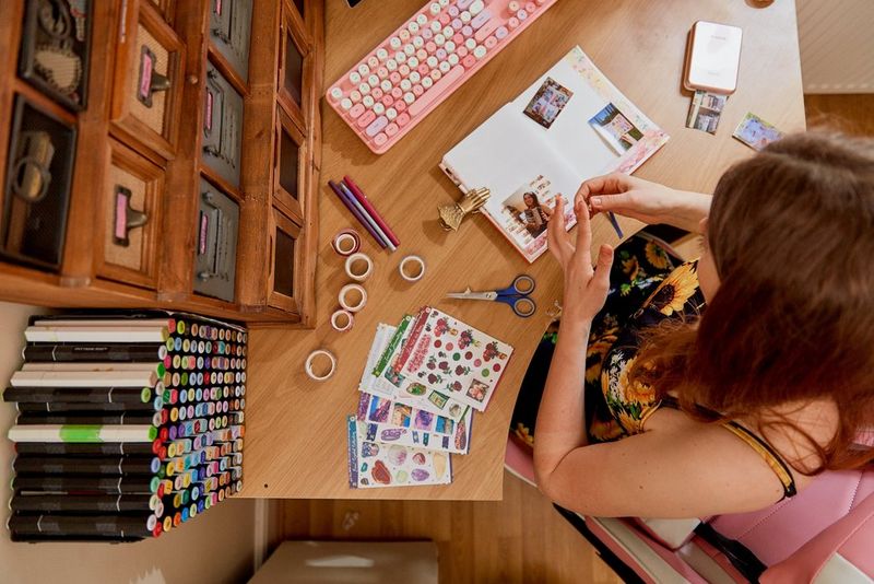 A top down image showing a woman's organised desk, with rolls of washi tape next to an open journal.