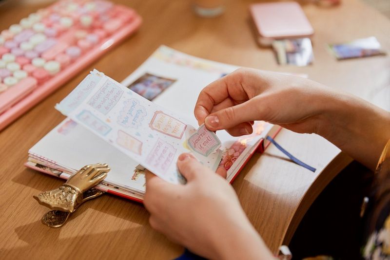 A person peeling a sticker off to place it into a journal.
