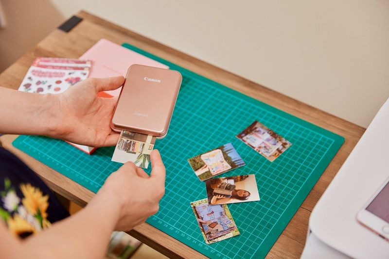 A person holding a Canon Zoemini as it prints out images.