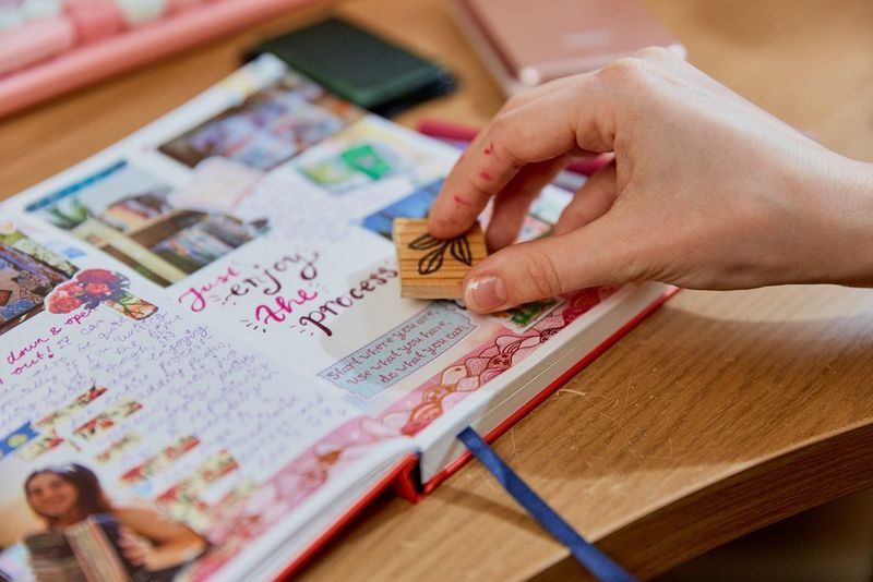 A person pressing down an ink stamp into a busy journal page.