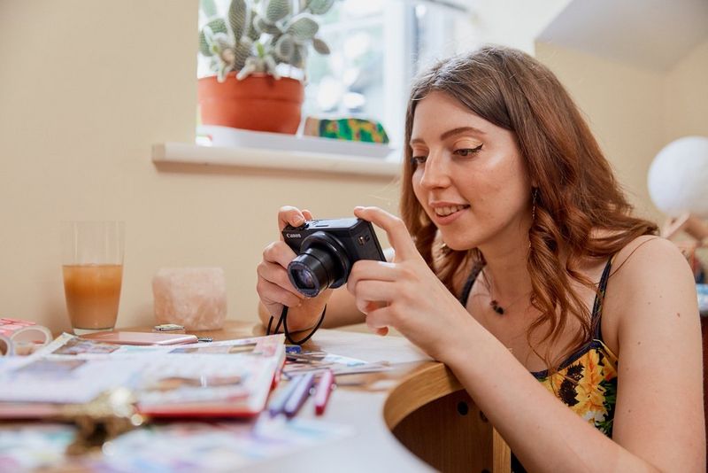 A woman photographing her open journal with her Canon PowerShot G7 X Mark III.