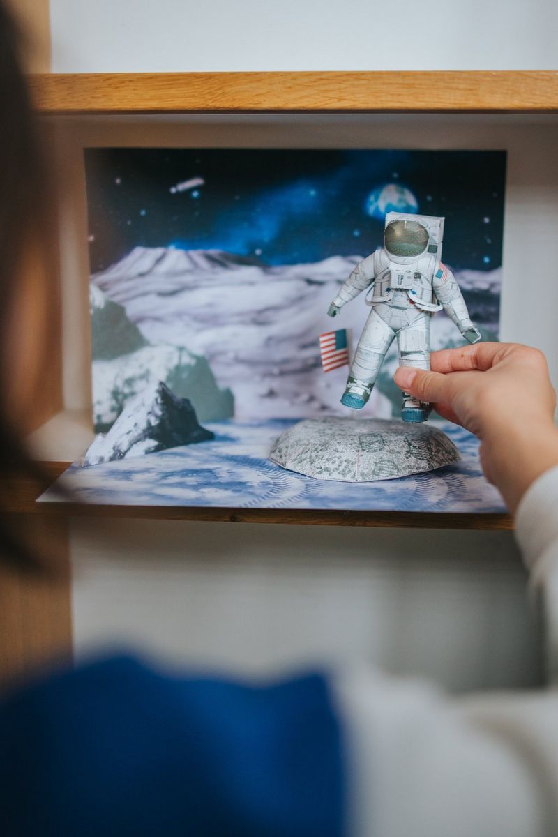 A child places a papercraft astronaut in a Creative Park Moon diorama.