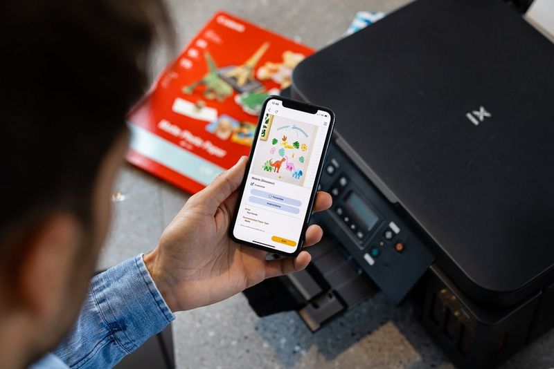 A man using his phone to wirelessly print on his PIXMA G6050 printer.