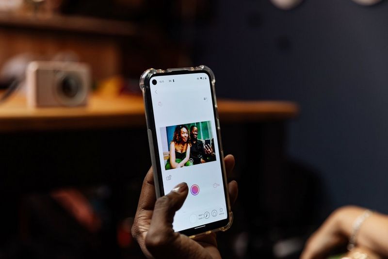 A hand holding a smartphone displaying the Live view mode in the Canon Mini Print app.