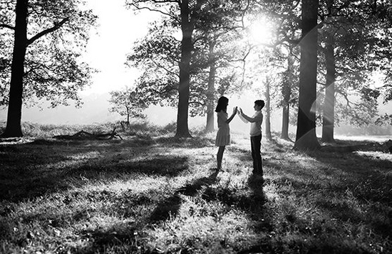 Two children silhouetted against a woodland background by the low sun streaming through the trees.