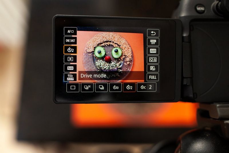 The vari-angle screen of a Canon camera, showing a 2-second timer set to photograph a plate of food.