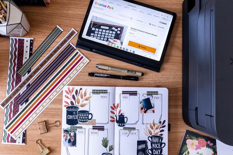 A top-down shot of an open bullet journal alongside border templates from Creative Park and a Canon PIXMA printer.