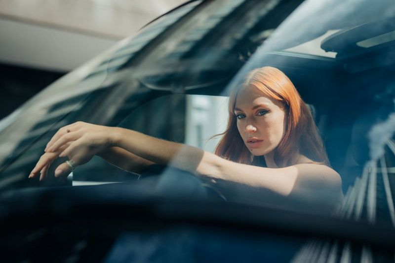 A woman leans against the steering wheel of a car in a commercial portrait taken on a Canon EOS R5 by Chris Priestley.