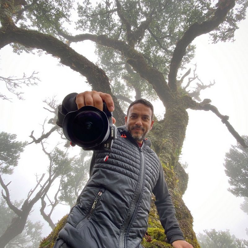Canon Ambassador Joel Santos standing below a large tree with his Canon camera. 