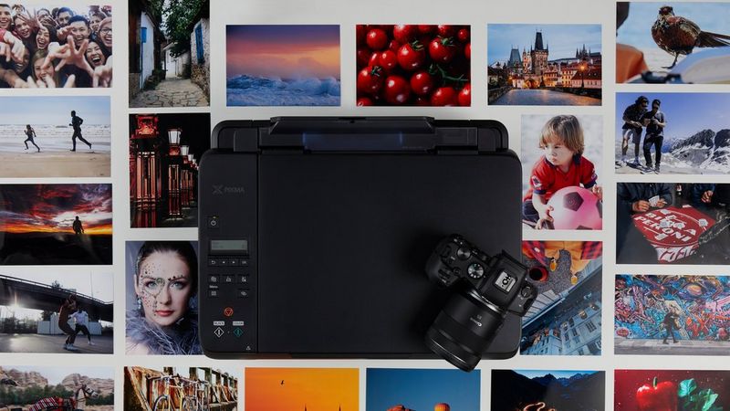A Canon PIXMA G650 with a camera on the top, surrounded by photo prints.