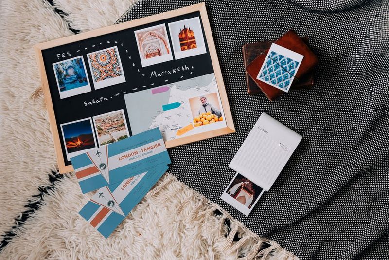 A travel-themed mood board on Morocco, showing tile patterns and tickets, next to a Canon SELPHY Square QX10. 