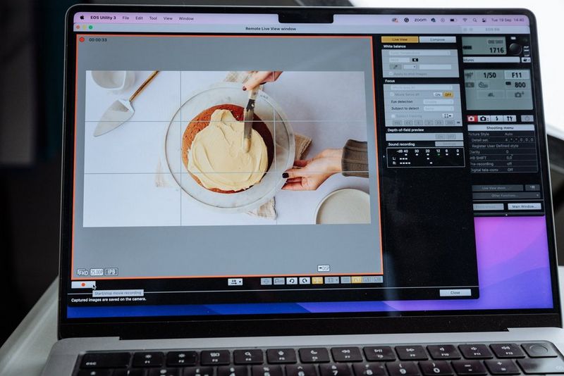A photograph of a hand swirling frosting on a cake, open in the Canon EOS Utility software on a laptop screen.