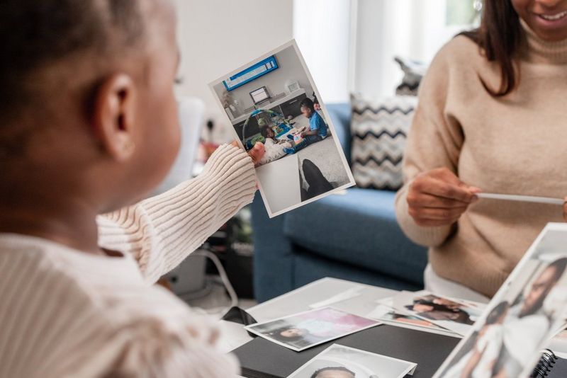 A young child looks through family photographs with her mother.