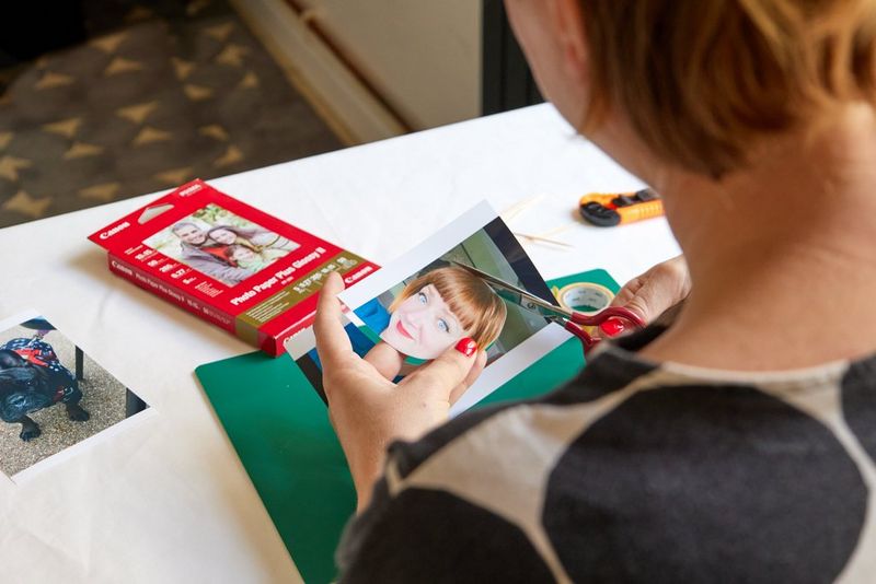An over-the-shoulder view of Pippa cutting out a photo of her face printed on Canon Glossy Photo Paper.