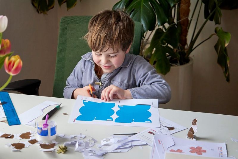 A young boy cuts out a Creative Park flower template with a pair of scissors.