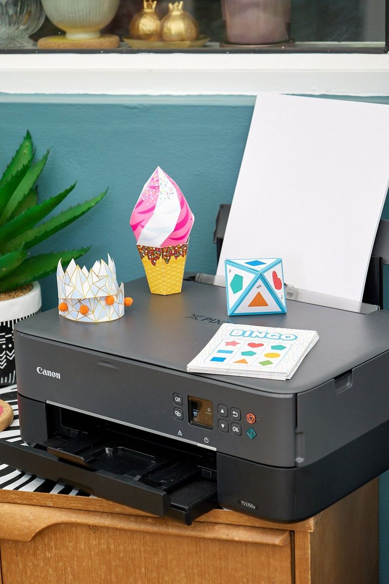 A Canon PIXMA printer with four picnic-themed papercrafts on top of it sits on a desk in a small room.