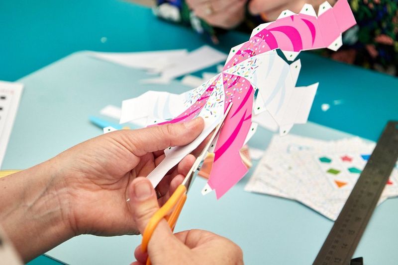 A pair of hands using scissors to cut out a Creative Park ice cream template.