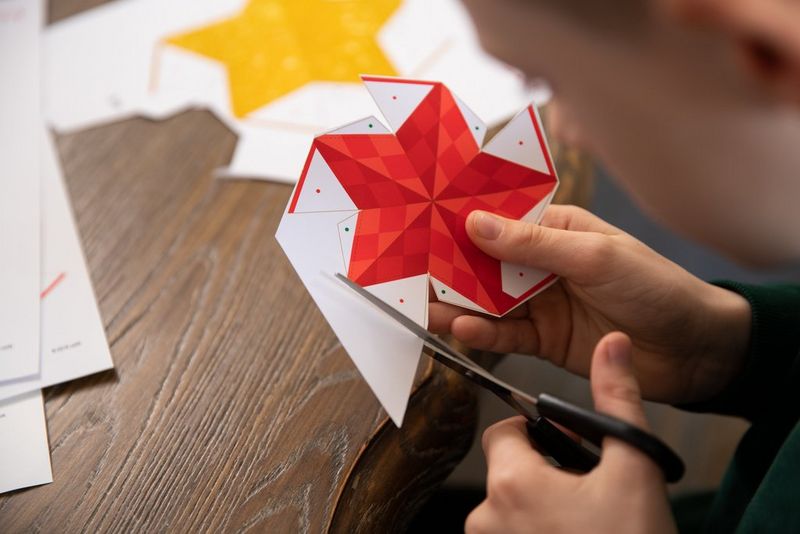 A boy's hands carefully cutting out a Creative Park papercraft star template.