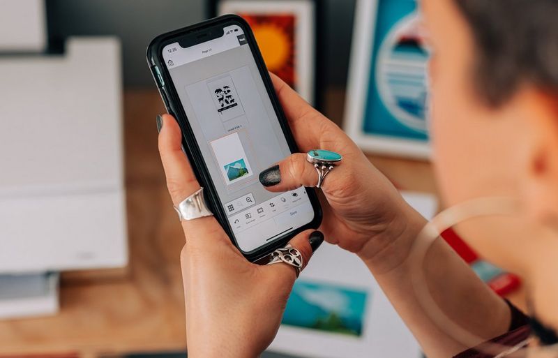 A woman using her phone to position two images on a piece of paper to print out