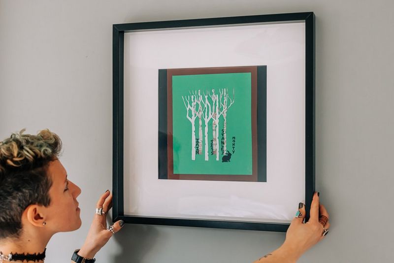 A green and white papercraft forest scene with names written alongside trees. 