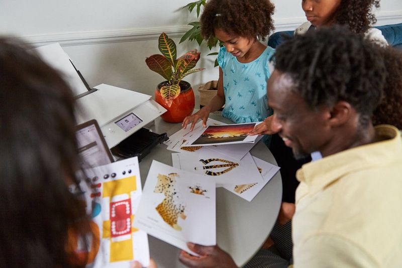 A series of templates of papercraft projects printed on A4 sheets, being passed around by a family.